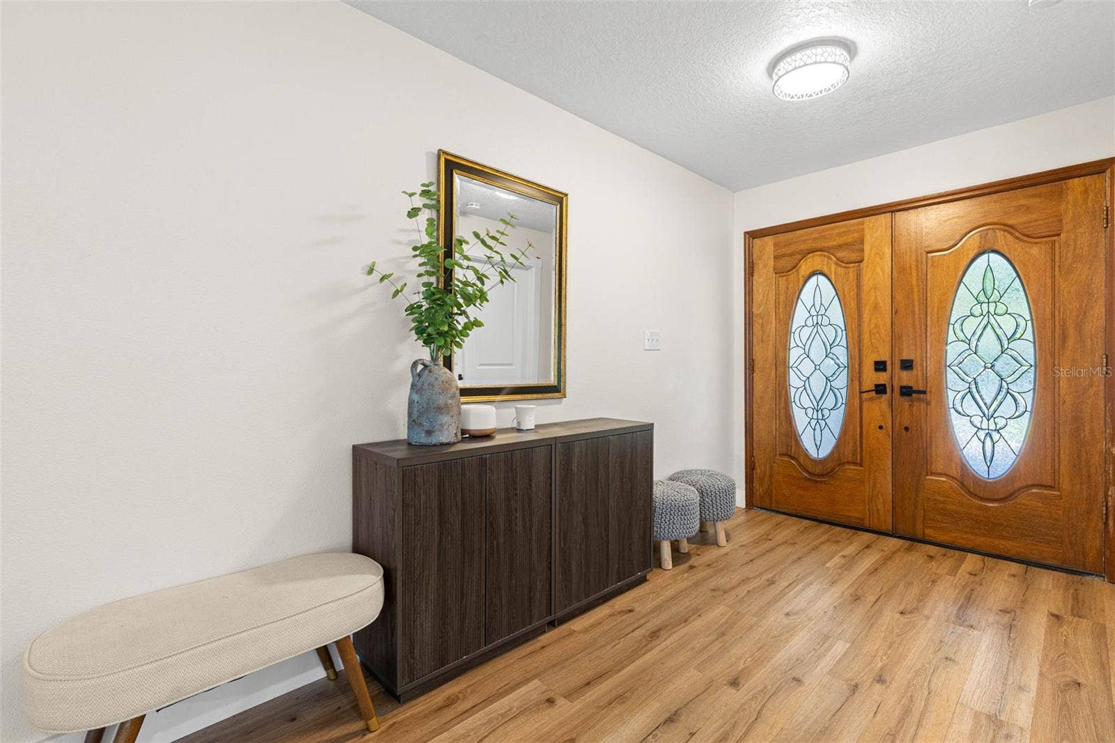3013 GRAHAM LANE, Tampa, FL 33618 A welcoming foyer highlights the distinctive double wood entry doors with decorative oval glass inserts, warm wood-look luxury vinyl flooring, and contemporary overhead lighting. The extended entryway offers plenty of room for a console table or additional seating.