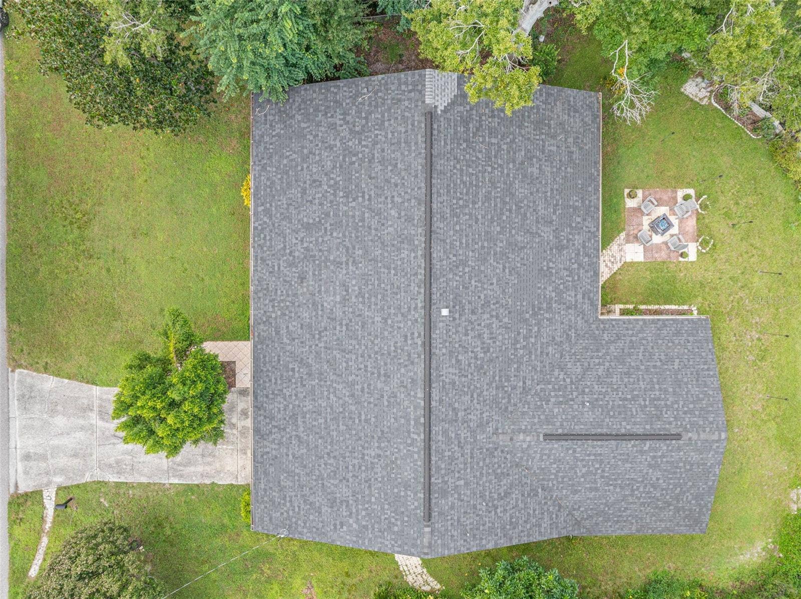 3013 GRAHAM LANE, Tampa, FL 33618 A bird-eye perspective highlights the home's expansive single-story footprint, dimensional shingle roof replaced in 2021, and surrounding lawn areas. The paver patio and fire pit area add character to the outdoor setting on this .34-acre property.