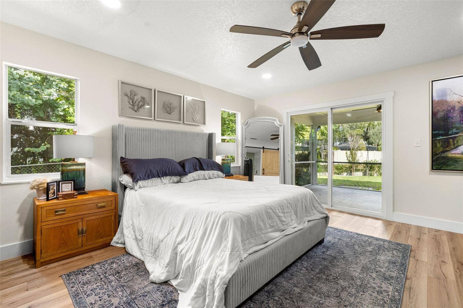 3013 GRAHAM LANE, Tampa, FL 33618 The primary bedroom offers a relaxing retreat with abundant natural light from multiple windows and sliding glass doors that open directly to the screened porch. Enjoy easy access to the outdoors, wood-look luxury vinyl flooring, and a contemporary ceiling fan.