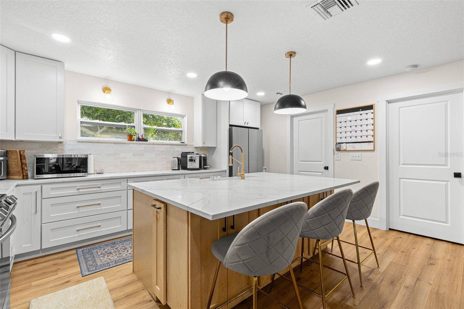 3013 GRAHAM LANE, Tampa, FL 33618 The oversized center island provides an expansive quartz countertop for meal preparation, casual dining, and entertaining. A gold gooseneck faucet, contemporary pendant lighting, abundant cabinetry, and a wide window above the counter add both style and functionality.