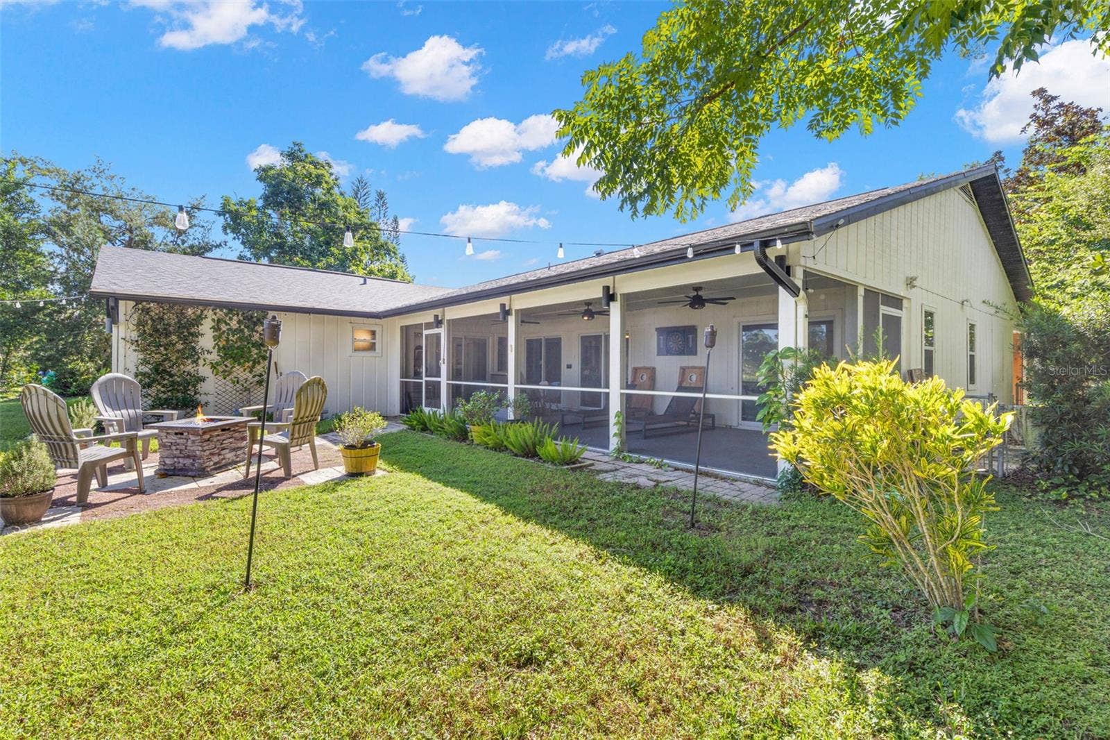 3013 GRAHAM LANE, Tampa, FL 33618 The beautifully landscaped backyard offers multiple opportunities for outdoor enjoyment, from the expansive screened porch to the open-air patio and fire pit area. Mature trees, colorful plantings, and overhead string lighting create an inviting setting for relaxing or entertaining.