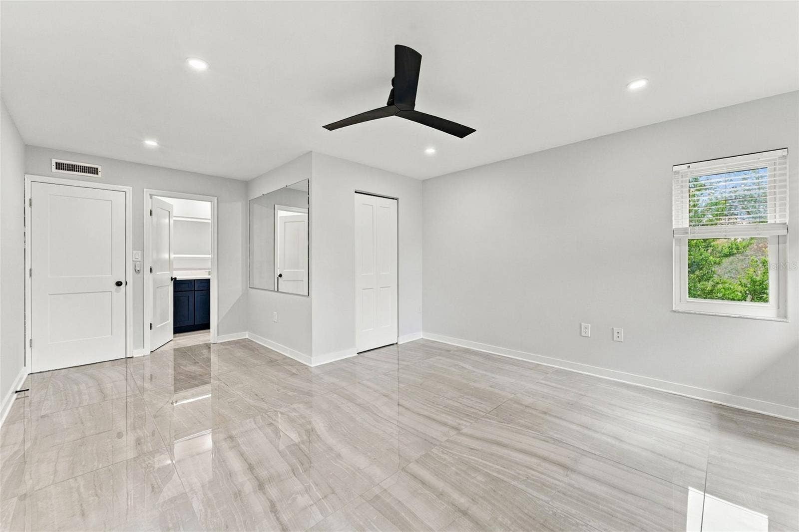 Generously sized primary bedroom with new flooring, lighting and ceiling fan