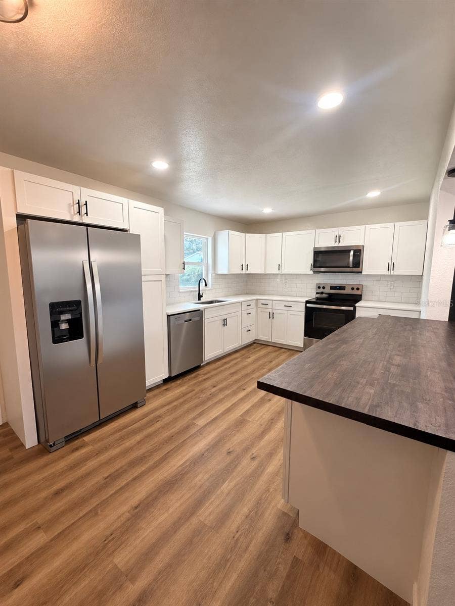 120 HAWTHORNE ROAD, Winter Haven, FL 33884 Updated kitchen featuring white shaker-style cabinetry, stainless steel appliances, subway tile backsplash, and expansive countertop space.