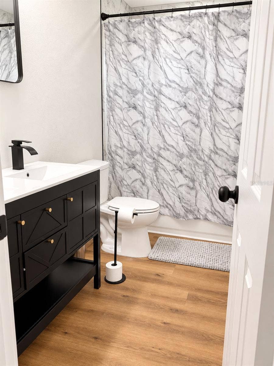 120 HAWTHORNE ROAD, Winter Haven, FL 33884 Updated bathroom featuring a, garden tub, contemporary black vanity, white countertop, and modern fixtures.