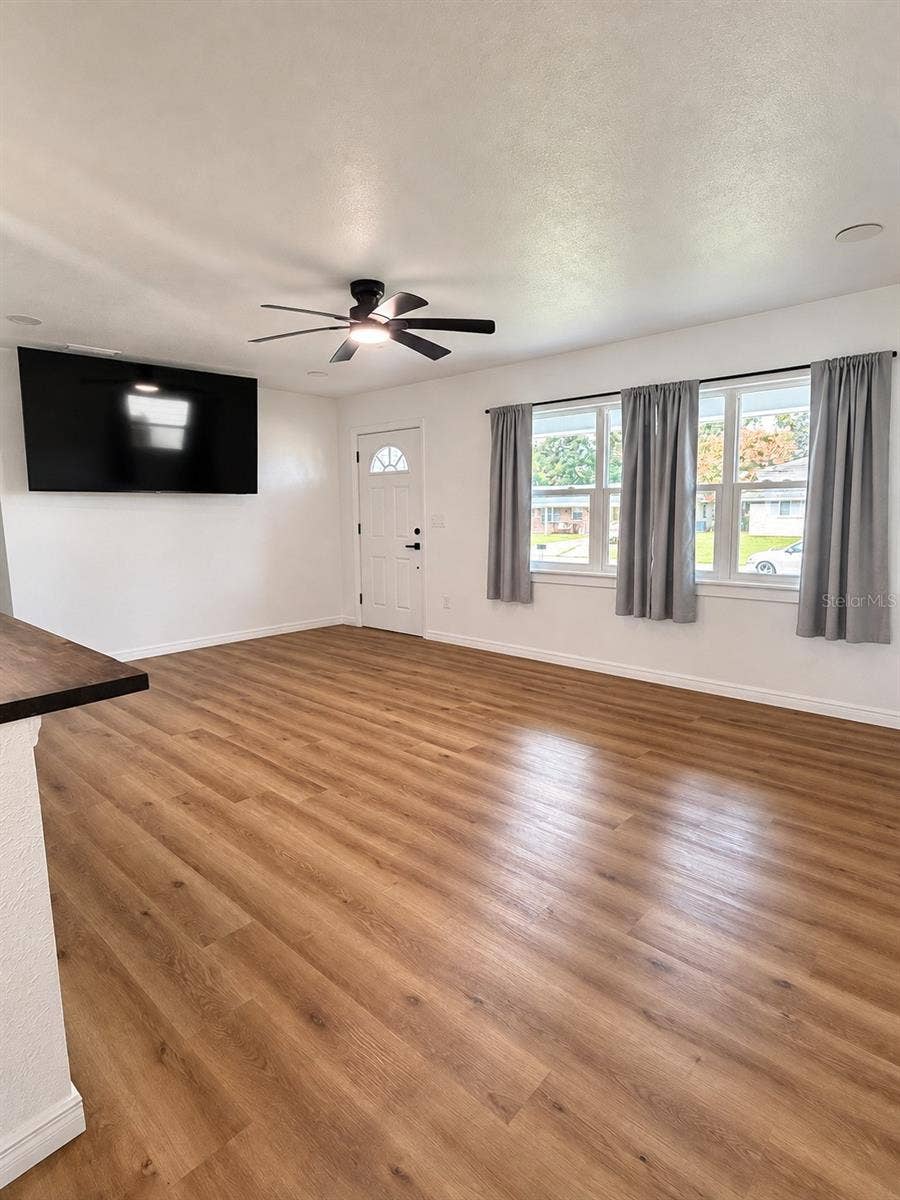 120 HAWTHORNE ROAD, Winter Haven, FL 33884 Bright and spacious living room featuring updated wood-look flooring, ceiling fan, and multiple windows providing natural light.