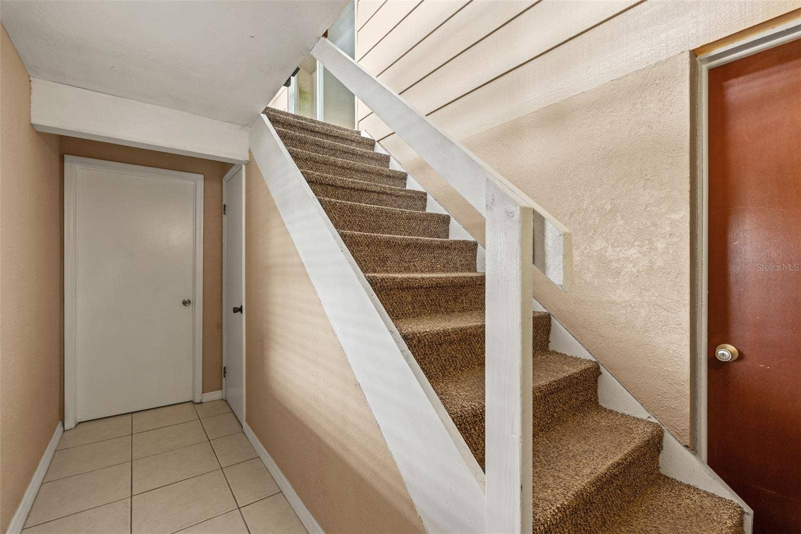 The interior stairway provides convenient access between the upper and lower levels. Neutral finishes, tile flooring, and nearby doorways connect the home's different living spaces.