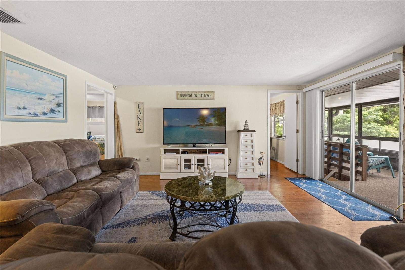 Indoor and outdoor living come together beautifully. The living room's sliding glass doors open to a spacious screened porch, while the stone fireplace adds warmth and character. It's a comfortable gathering space in every season.