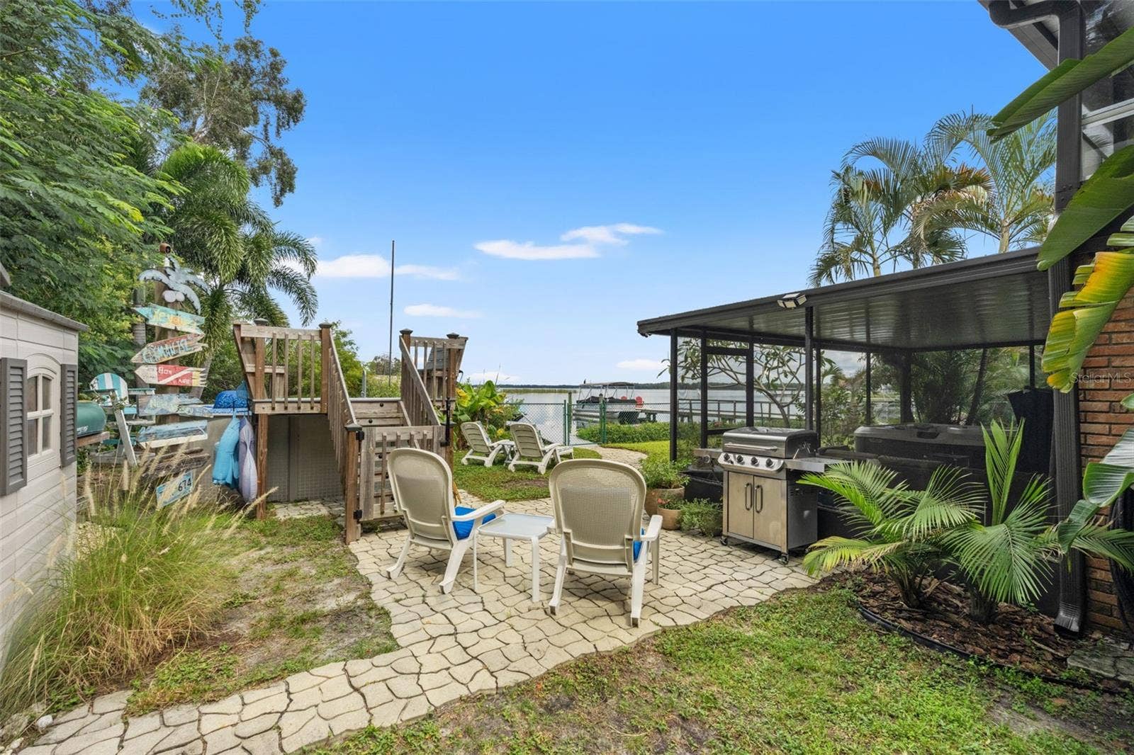 There's plenty of room to enjoy the Florida lifestyle! This backyard gathering area features a paver patio, grilling station, lounge seating, and an above-ground pool with a raised deck. Just beyond, the waterfront and dock create a beautiful backdrop for outdoor entertaining.