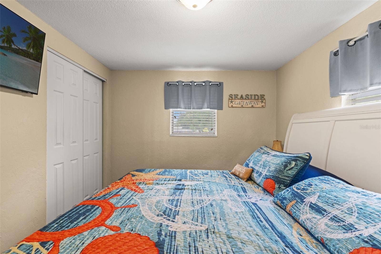 Another view of this inviting bedroom highlights the double-door closet, wood flooring, and natural light from two windows. A comfortable space for family or overnight guests.