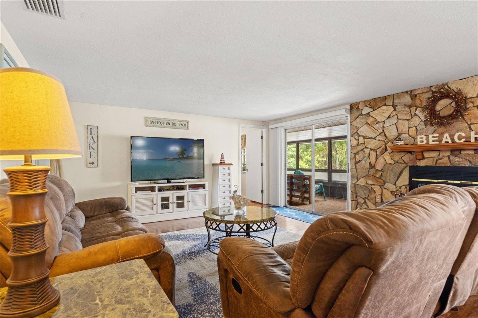 Comfortable, inviting, and full of character! The living room offers generous seating space, warm wood flooring, and direct access to a screened porch. The stone fireplace adds a cozy touch to this waterfront retreat.