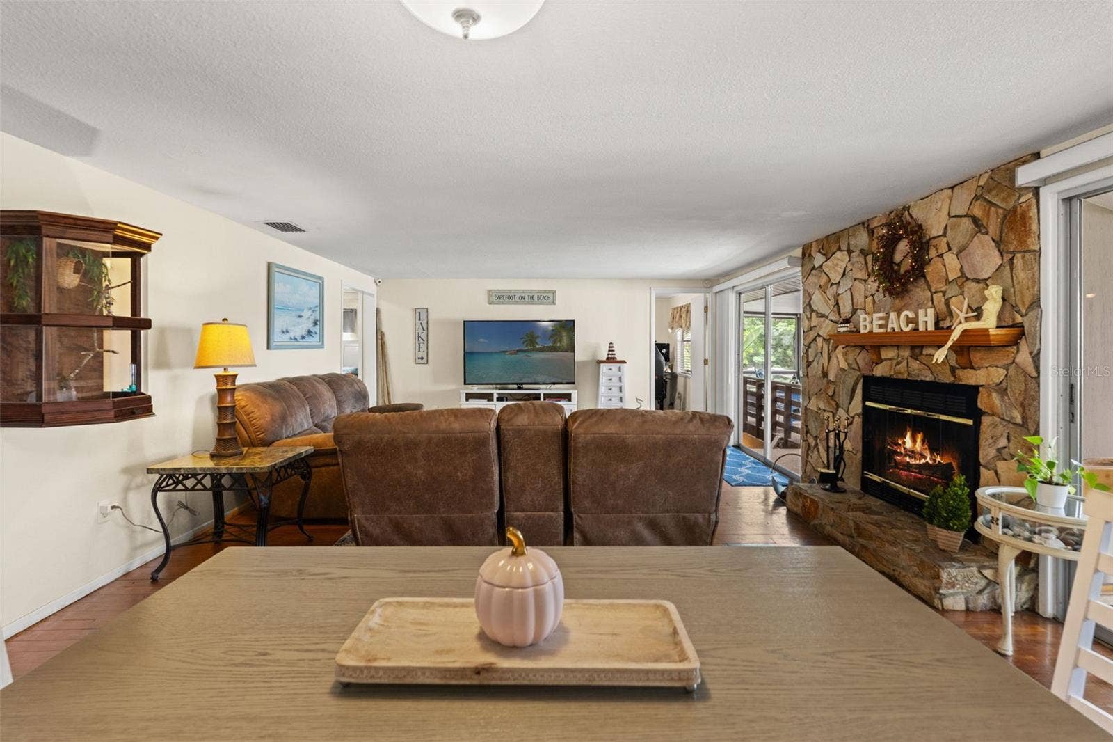 A beautiful stone fireplace brings warmth and character to the living room! The generous seating area features wood flooring and sliding glass doors leading toward the covered outdoor space.