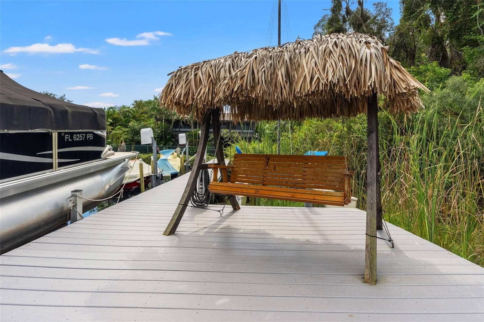 A little slice of paradise right on the water! The dock features a wooden swing beneath a tropical thatched roof, creating a shaded place to relax beside the lake. It's an inviting spot to unwind after boating or simply enjoy the waterfront atmosphere.