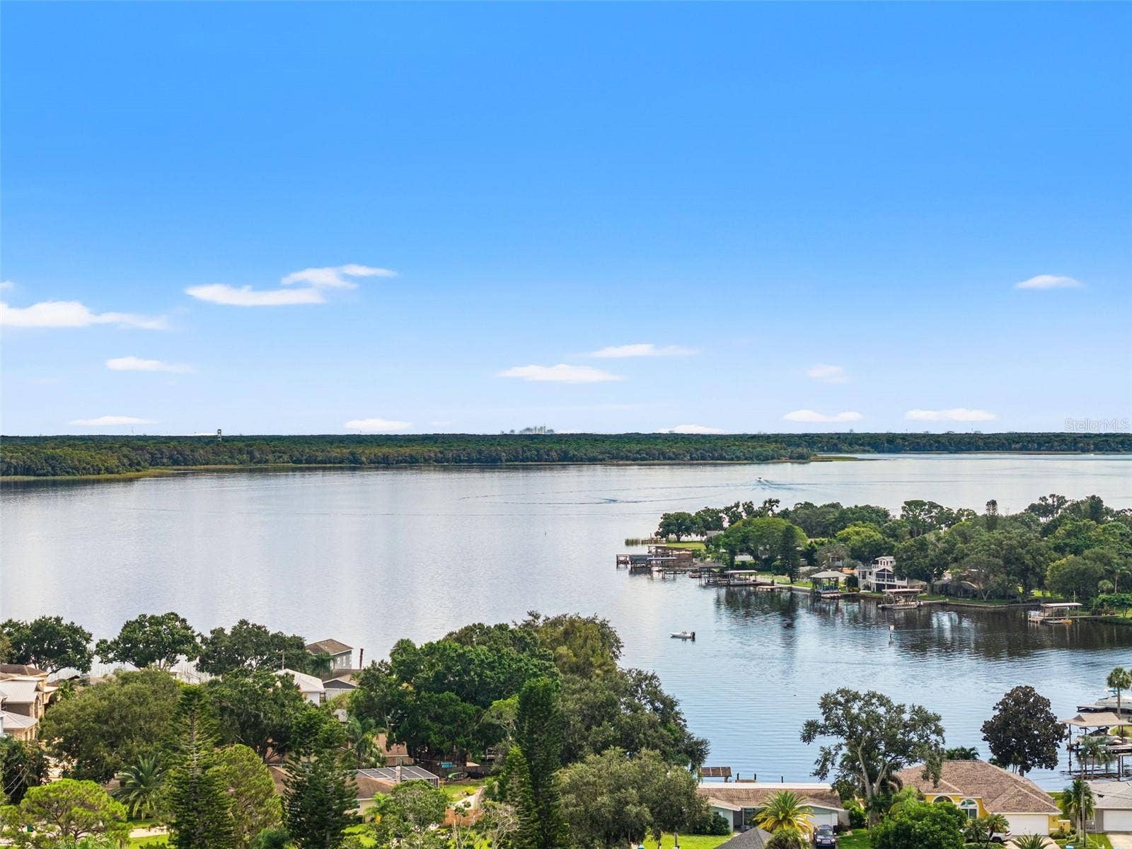 An expansive aerial view captures the beauty of the lake, with broad stretches of open water, natural shoreline vegetation, and distant tree-lined banks. It's a setting that invites afternoons on the boat, peaceful mornings by the water, and an appreciation for Florida's natural scenery.