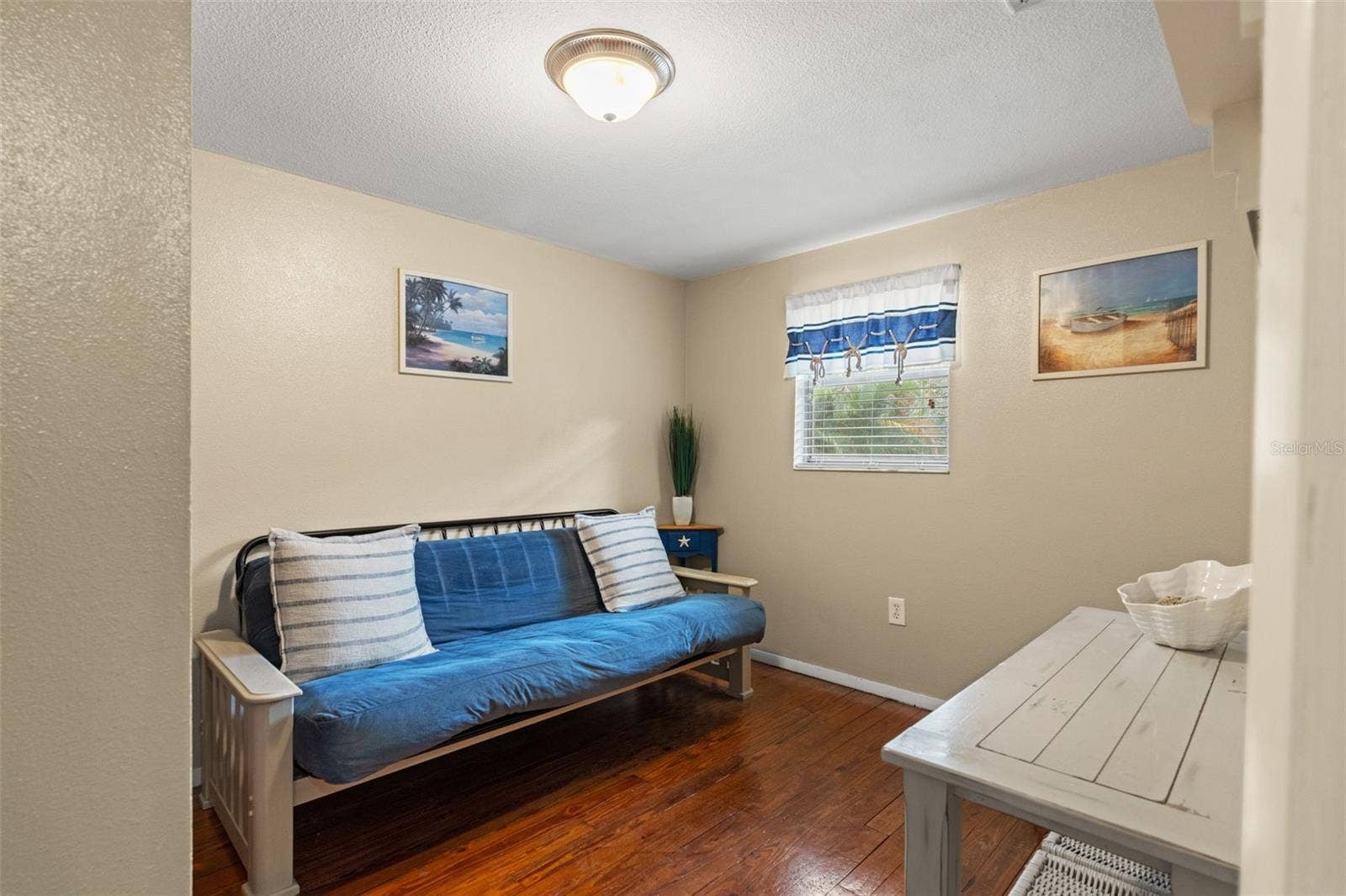 Need a home office, guest room, or quiet retreat? This versatile room features wood flooring, natural light, and space for a variety of furniture arrangements. Currently furnished with a futon, it offers flexibility to suit your needs.