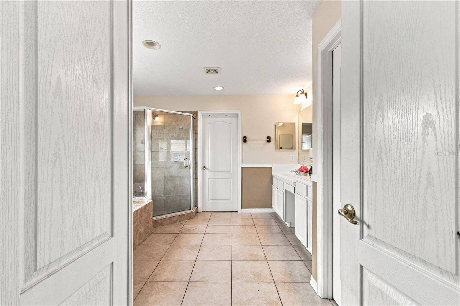 The primary bathroom entry features double doors offering a spa like feel.