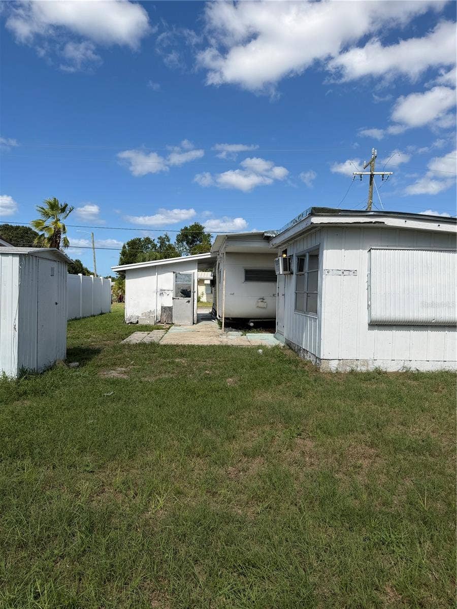 4120 BUENA VISTA LANE, Holiday, FL 34691 View of the fenced in backyard. Building on the left is storage and the laundry room is across from the main mobile.