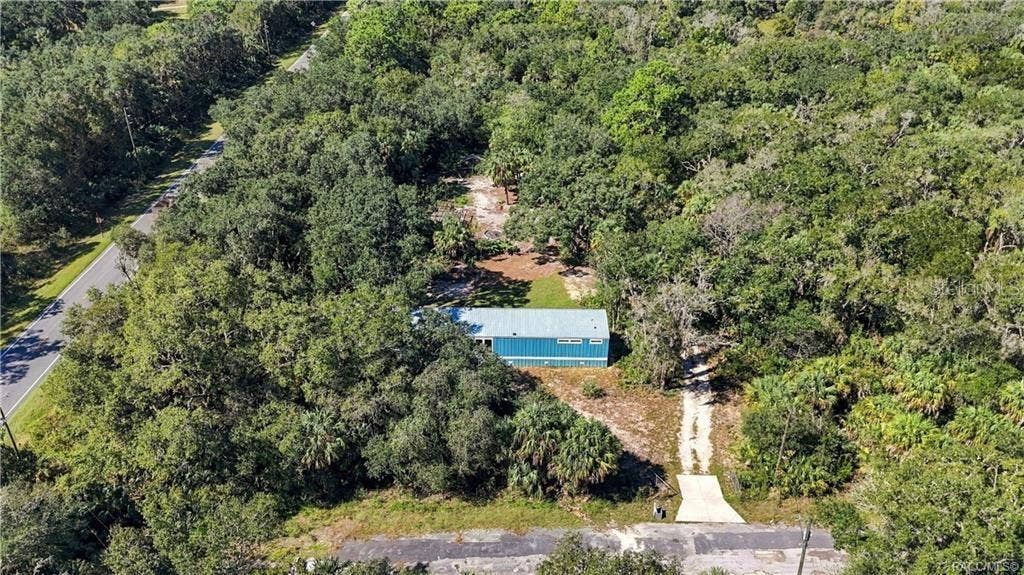 7528 N CHABAUD TERRACE, Crystal River, FL 34428 A BIRD'S-EYE VIEW! An aerial perspective showcases the home's wooded surroundings, natural landscape & driveway leading to the property.