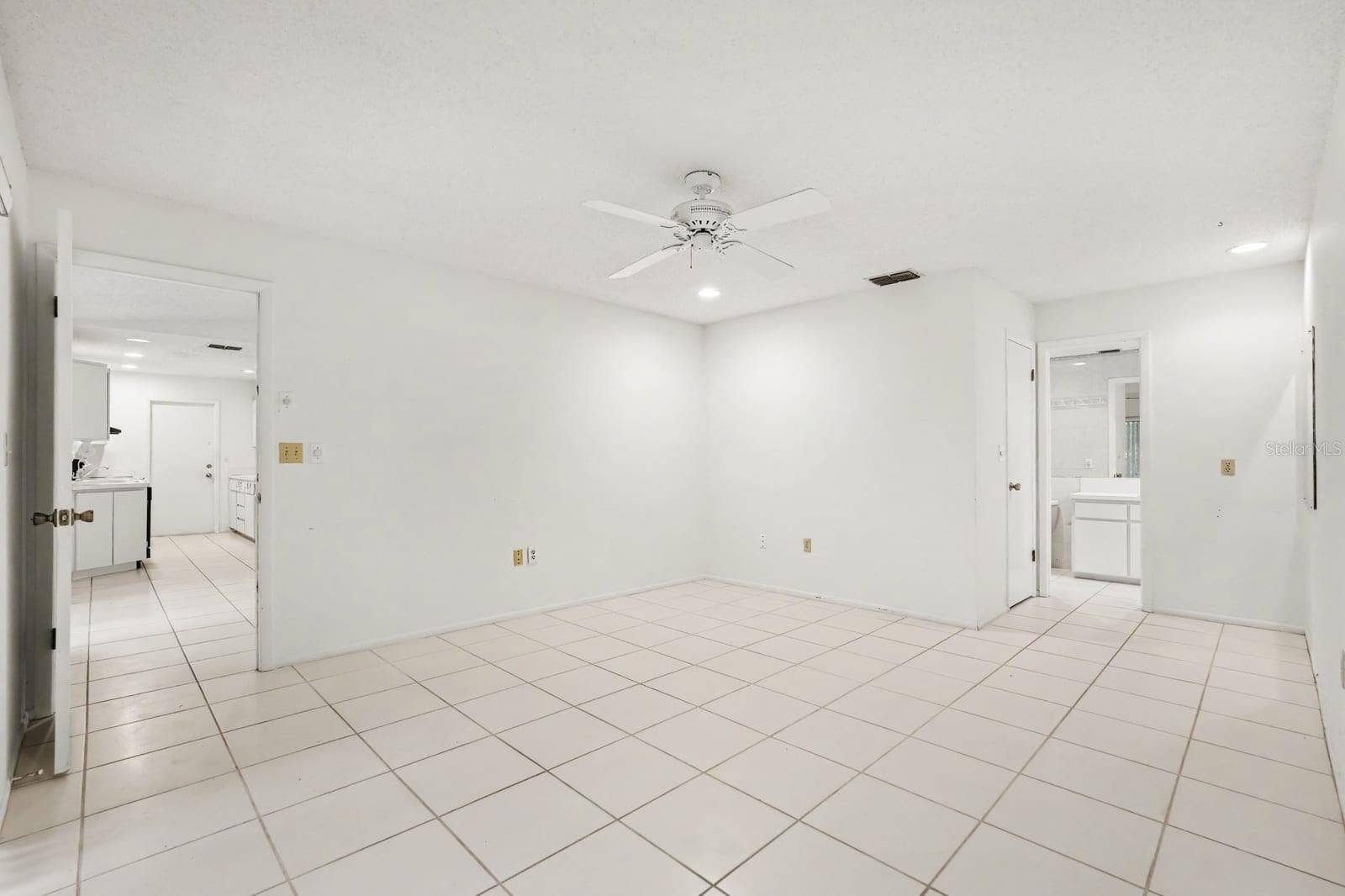 Open Living Area with Tile Floors, Ceiling Fan, and Dual Access Doors