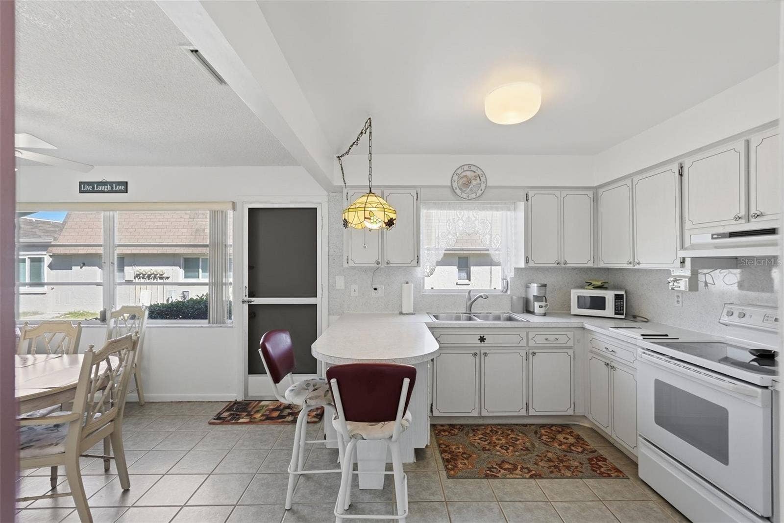 7035 MONTE CARLO N, Pinellas Park, FL 33781 Bright kitchen with white cabinetry, appliances, and adjacent dining space.