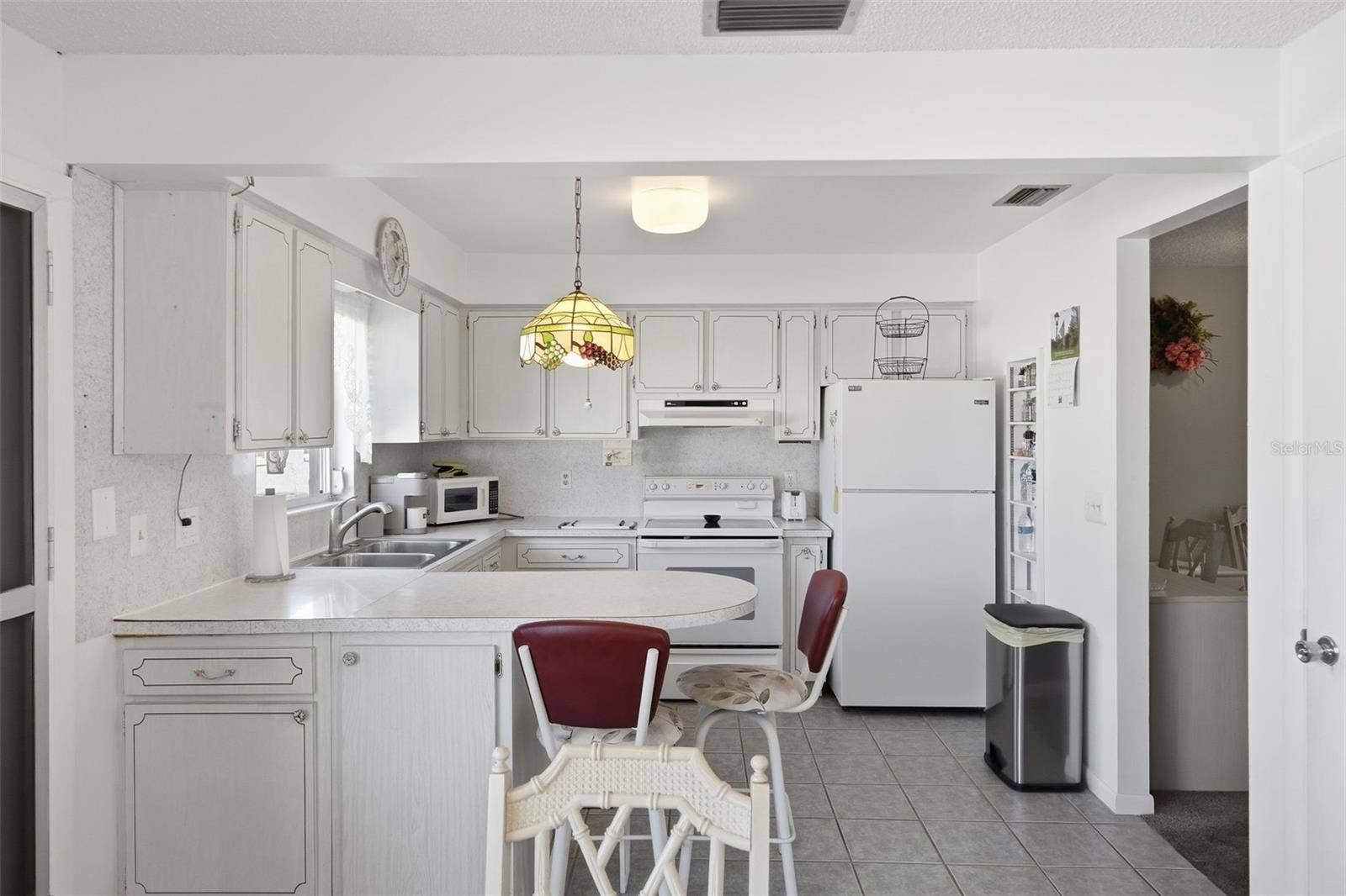 7035 MONTE CARLO N, Pinellas Park, FL 33781 Open view of the kitchen and dining area with bright white finishes.