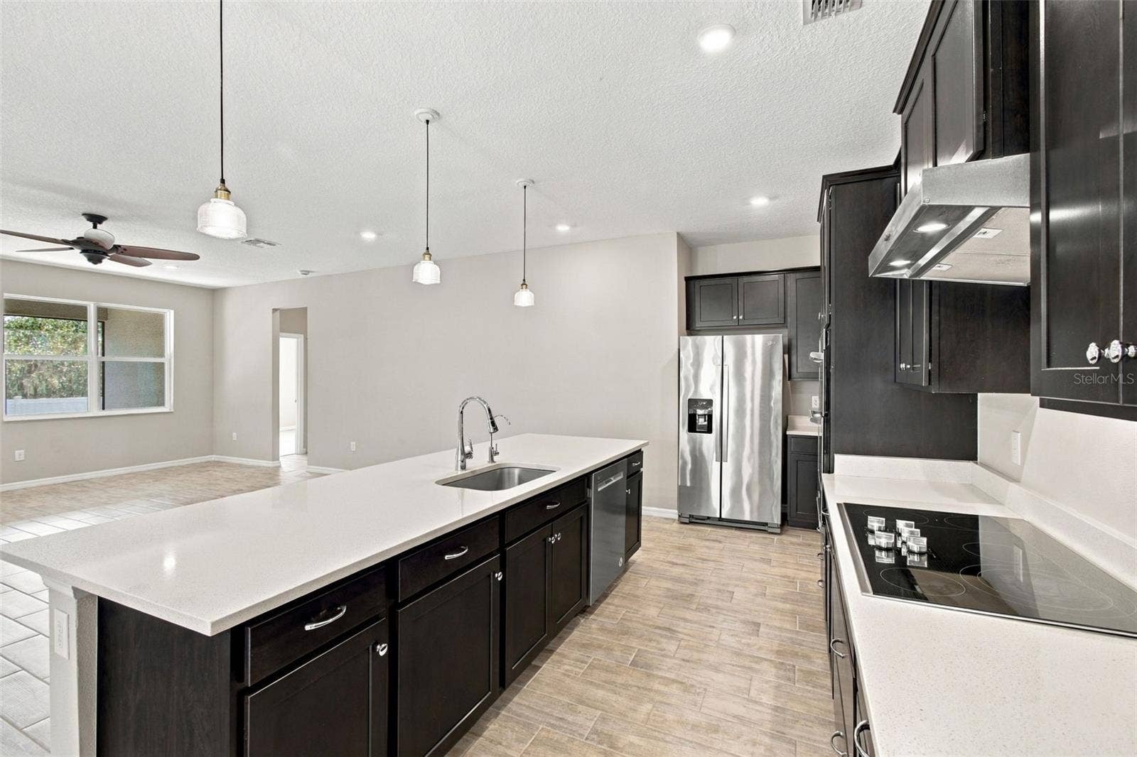 12417 BRICK COBBLESTONE DRIVE, Riverview, FL 33579 Kitchen with solid deep wood cabinets, quartz counters, and chic pendant lights - cooktop with range hood to the right