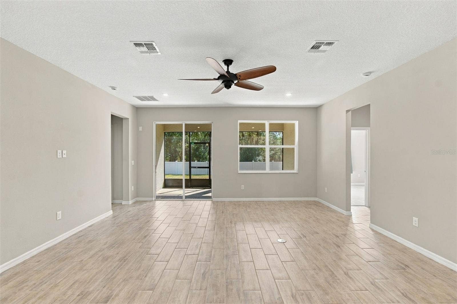 12417 BRICK COBBLESTONE DRIVE, Riverview, FL 33579 Living Room - to the left: entrance to primary suite, to the right: hall leading to two additional bedrooms and full bath - screened in patio in background