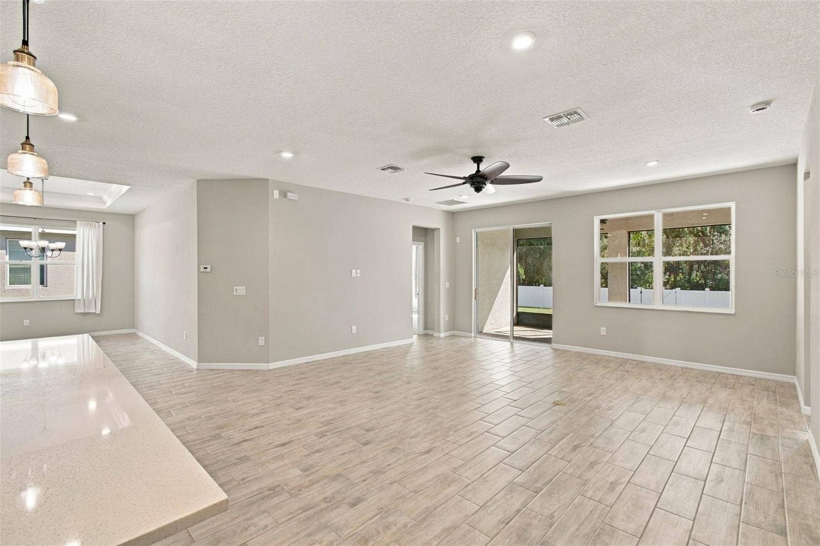12417 BRICK COBBLESTONE DRIVE, Riverview, FL 33579 Spacious living room with ceiling fan - patio in background to the right, dining room to the left