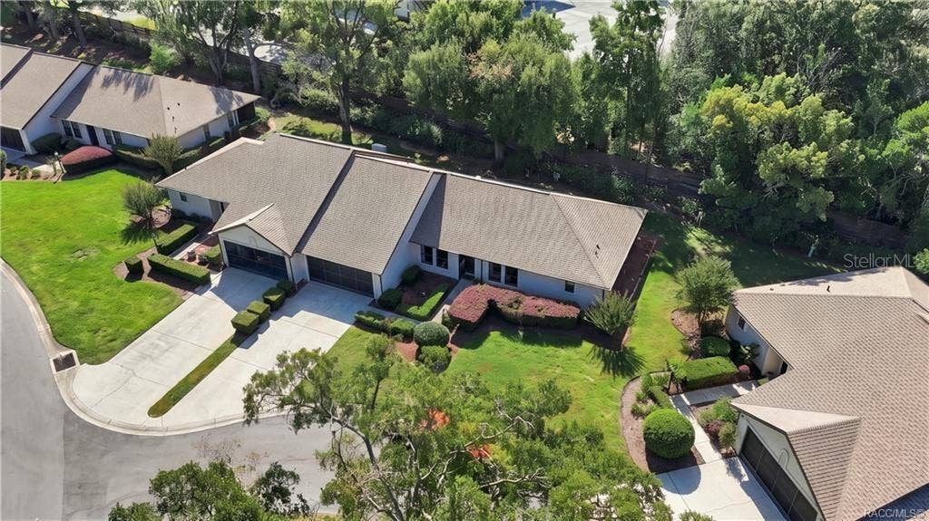 6268 W WESTON DRIVE, Crystal River, FL 34429 Aerial perspective showcasing the home's roofline, beautifully maintained grounds, surrounding residential properties, and wooded backdrop.