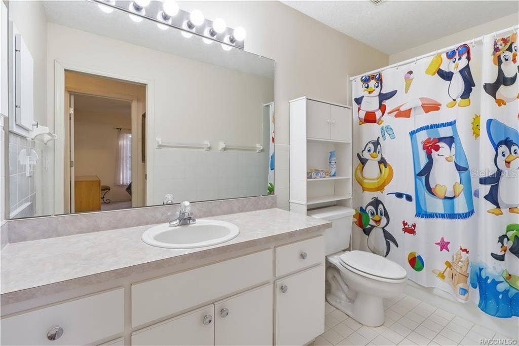 6268 W WESTON DRIVE, Crystal River, FL 34429 Guest bathroom with white cabinetry, extended vanity countertop, large wall mirror, and tub/shower combination.