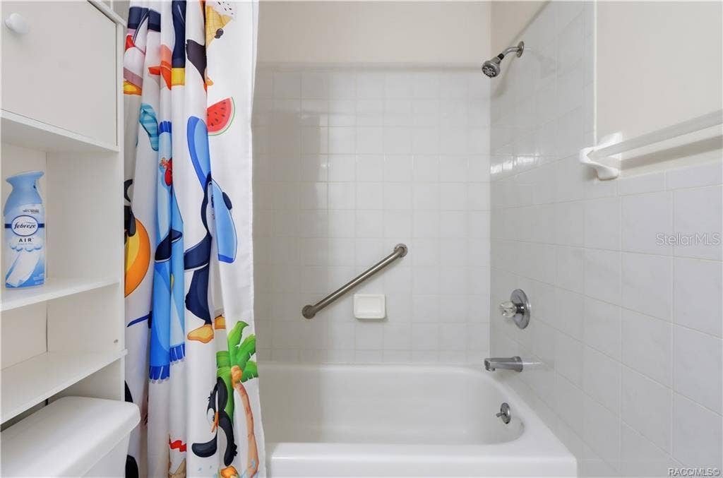 6268 W WESTON DRIVE, Crystal River, FL 34429 Tub/shower combination featuring white tile surround, built-in soap dish, and grab bar.