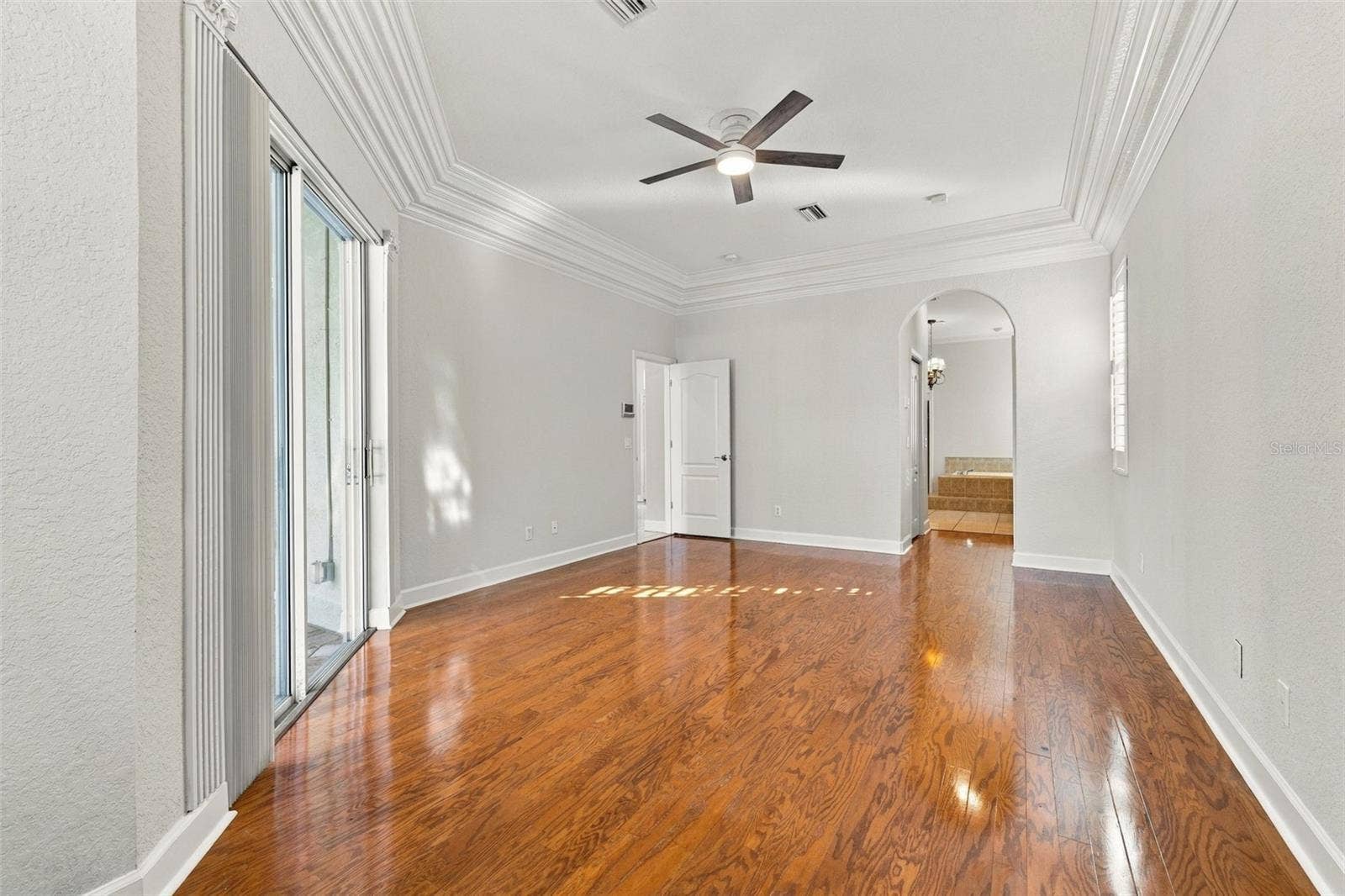 3916 VALRICO GROVE DRIVE, Valrico, FL 33594 Primary Bedroom with Double Step Tray Ceiling adorned with Crown Molding, Sliding Glass Door to Pool/Spa area & Real Wood Floors!