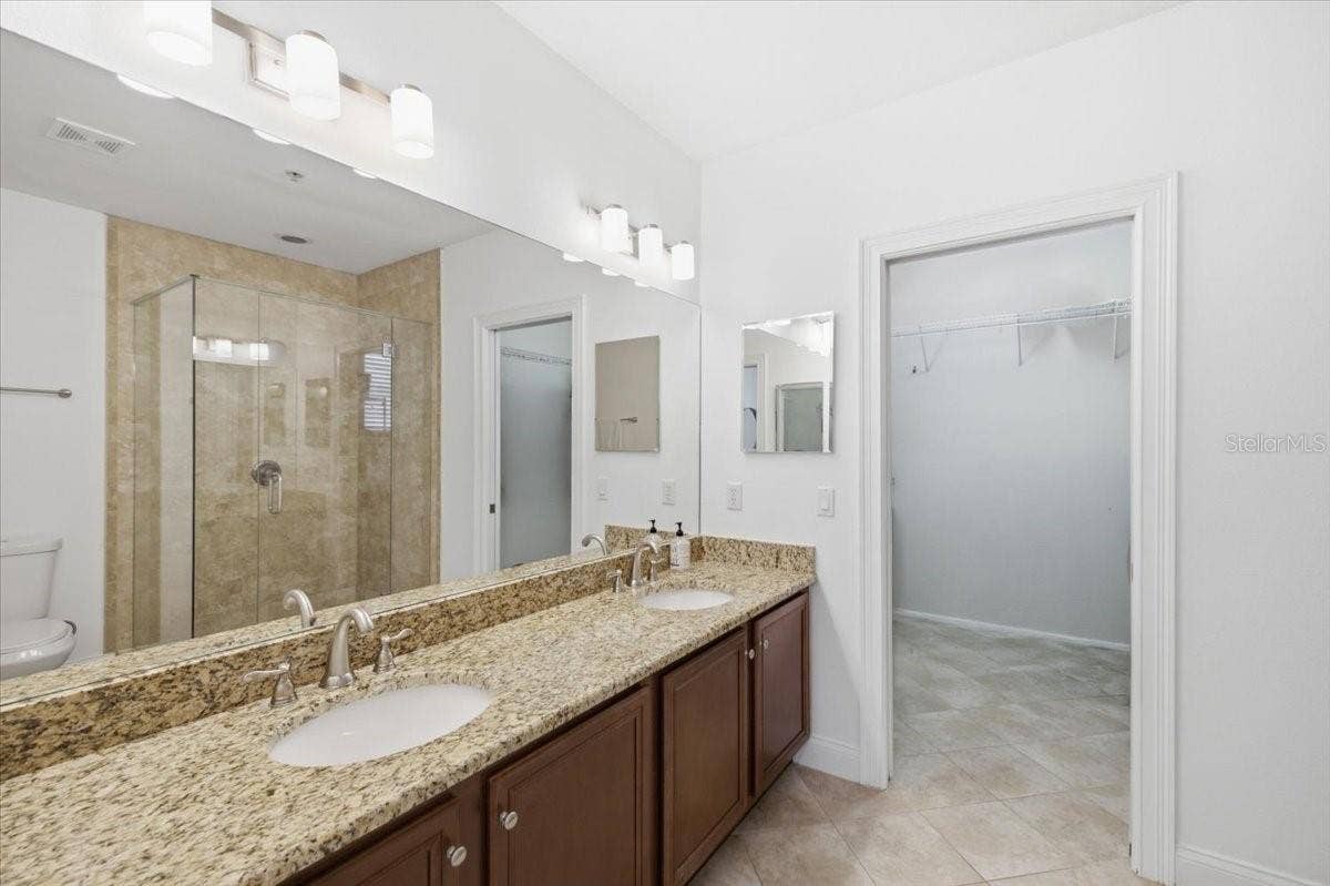 En suite primary bathroom with dual sinks and walk in shower.