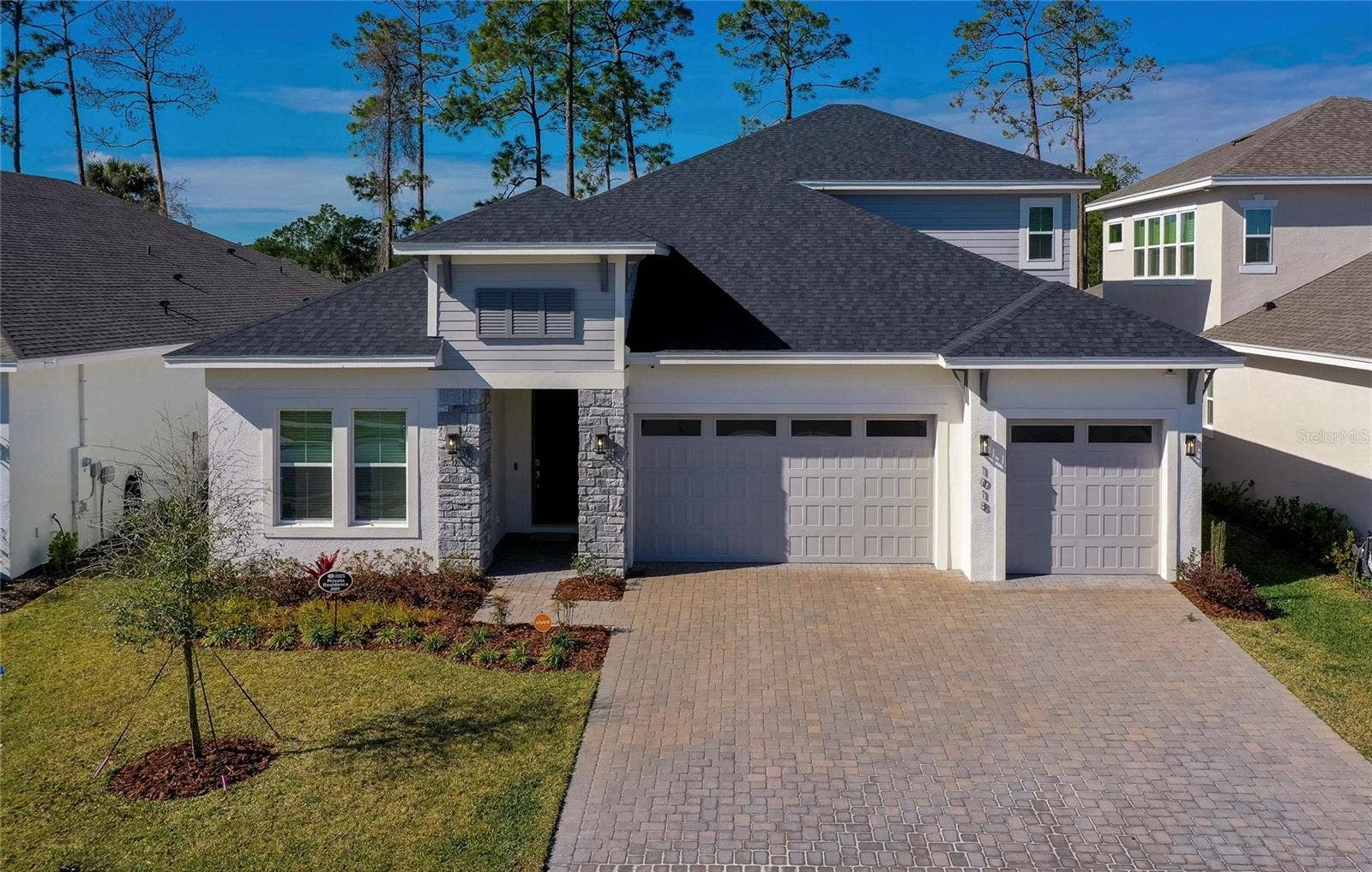 1018 FLOPSHOT CIRCLE, Daytona Beach, FL 32124 Beautifully maintained exterior with a three-car garage, paver driveway, and a welcoming stone-accented entryway. Thoughtful landscaping enhances curb appeal.