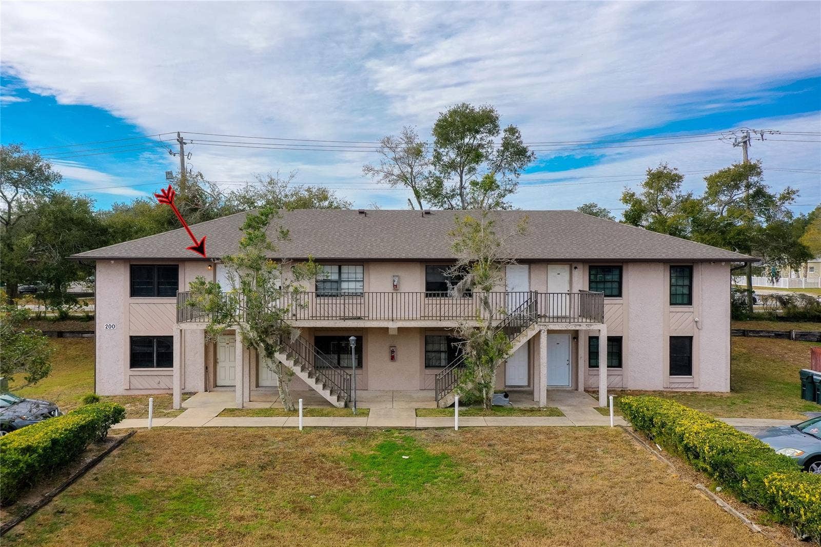 1290 9TH STREET, #205, Daytona Beach, FL 32117 Upstairs unit highlighted in this well-maintained two-story complex with mature trees, exterior stair access, and a neatly landscaped front lawn.