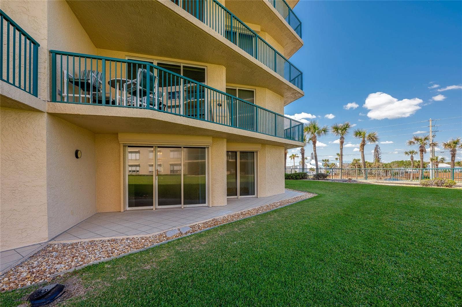 4575 S ATLANTIC AVENUE, #6101, Port Orange, FL 32127 A spacious outdoor patio area with direct access to landscaped green space, ideal for enjoying the outdoors or entertaining.