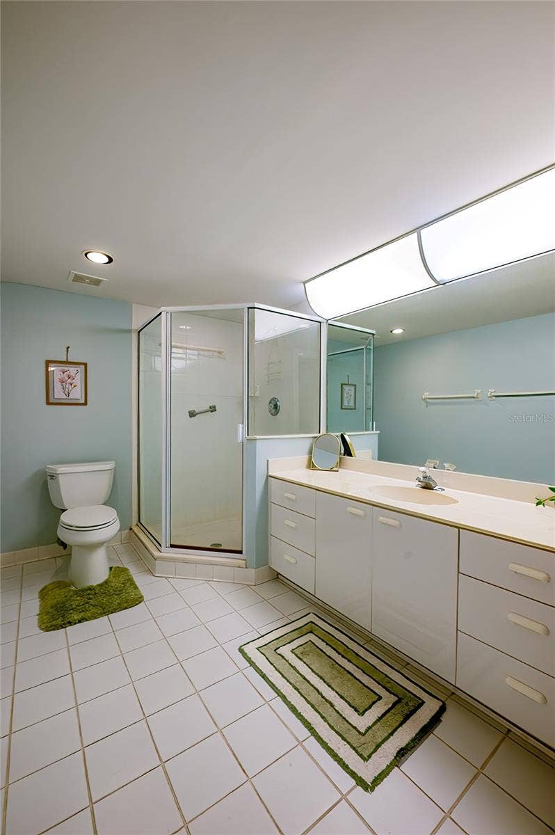 4575 S ATLANTIC AVENUE, #6101, Port Orange, FL 32127 A well-appointed bathroom featuring a spacious vanity with ample storage, a large mirror, and a glass-enclosed shower, offering both functionality and comfort.