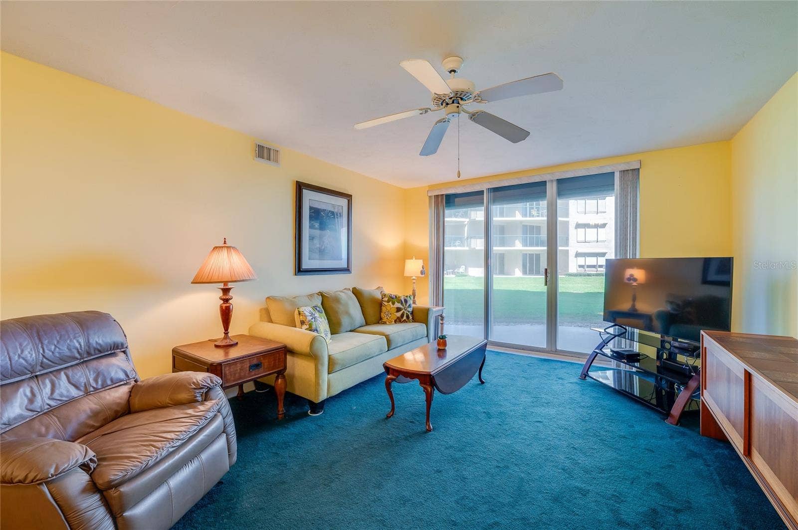 4575 S ATLANTIC AVENUE, #6101, Port Orange, FL 32127 This comfortable living area features a ceiling fan, and large sliding glass doors that bring in natural light and offer direct access to outdoor views.