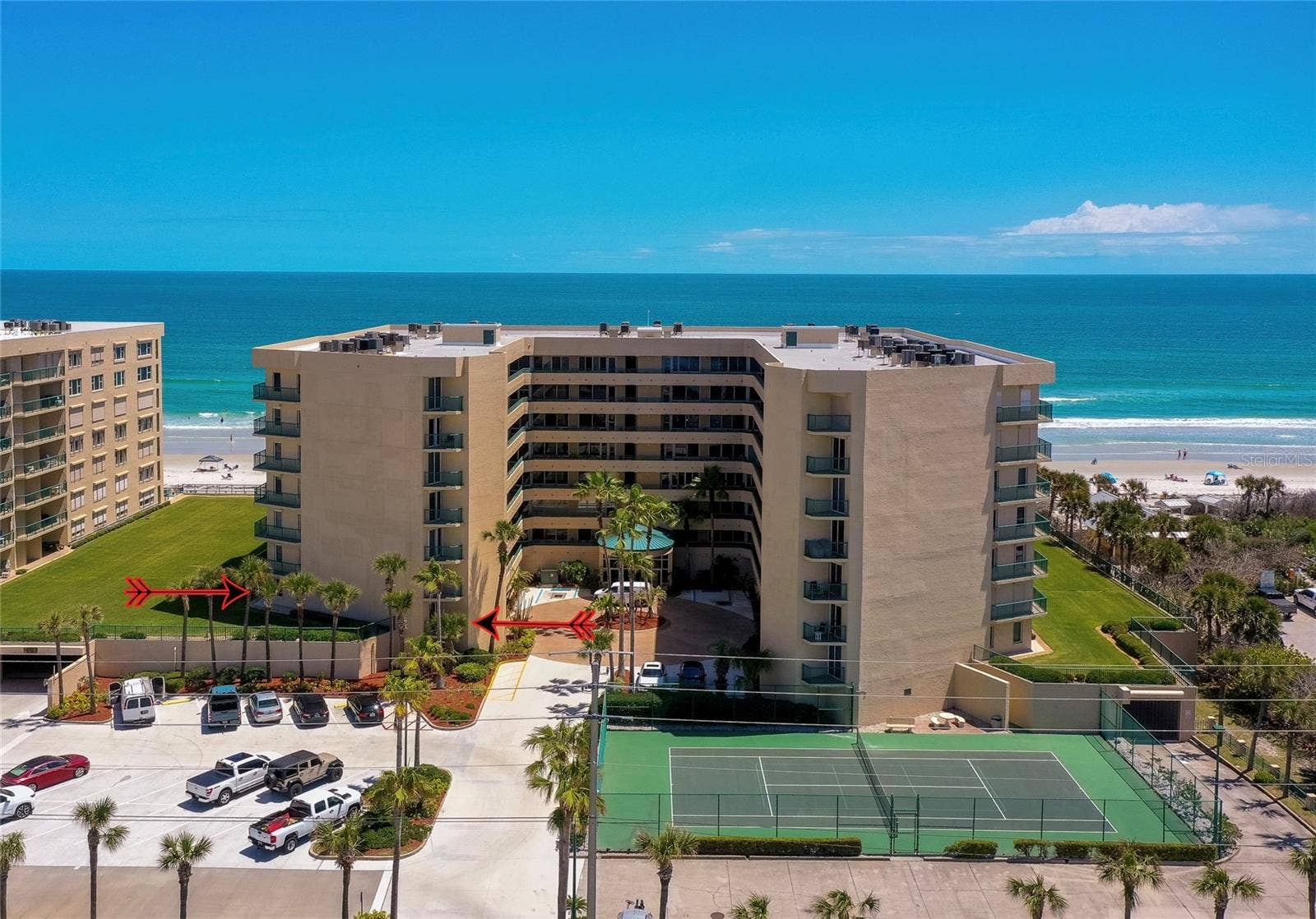 4575 S ATLANTIC AVENUE, #6101, Port Orange, FL 32127 Elevated view highlighting the buildings main entrance, guest parking, and on-site tennis courts, all just moments from the beach.