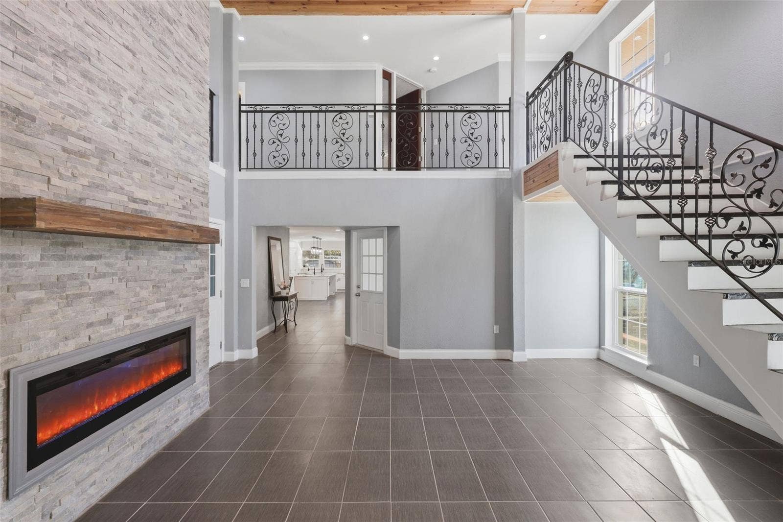 5414 RIVERSIDE DRIVE, Port Orange, FL 32127 Main Living Area with floor to ceiling fireplace mantel and custom wrought- iron staircase leading all the way up to the Third floor.