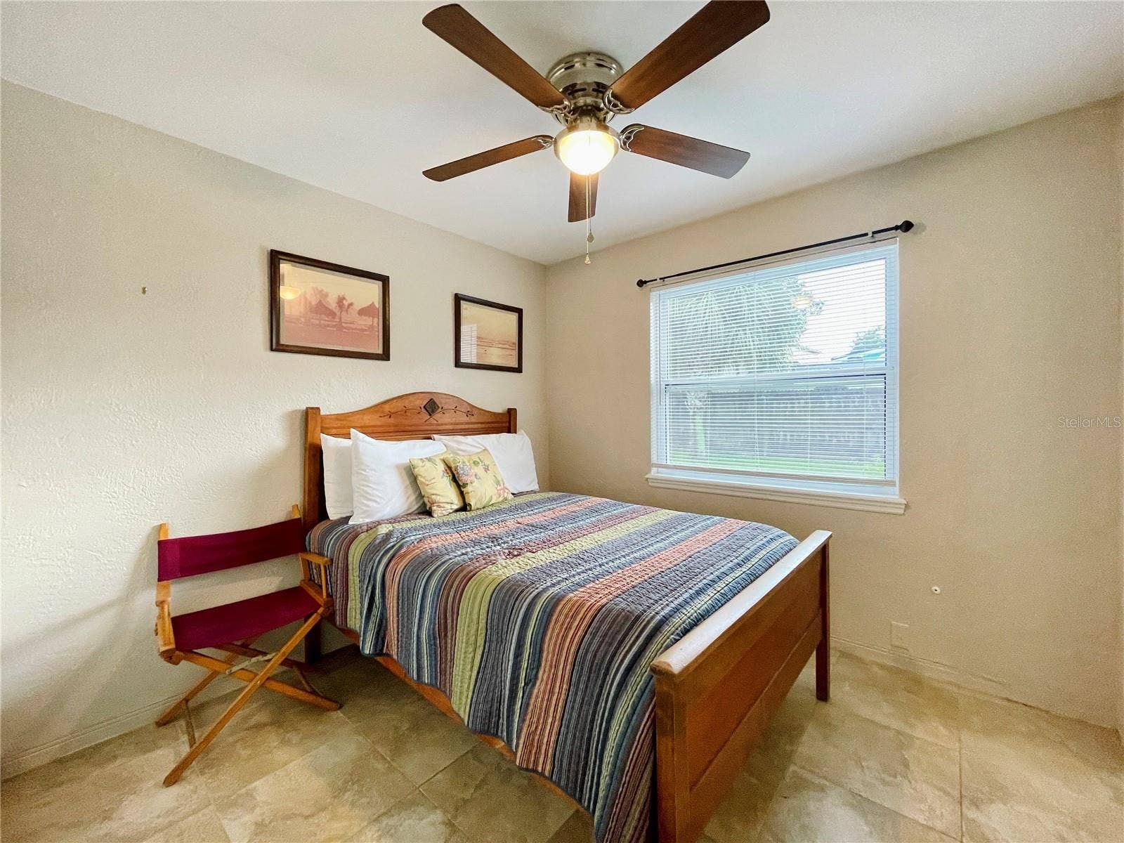 Cozy bedroom featuring a ceiling fan and large window.