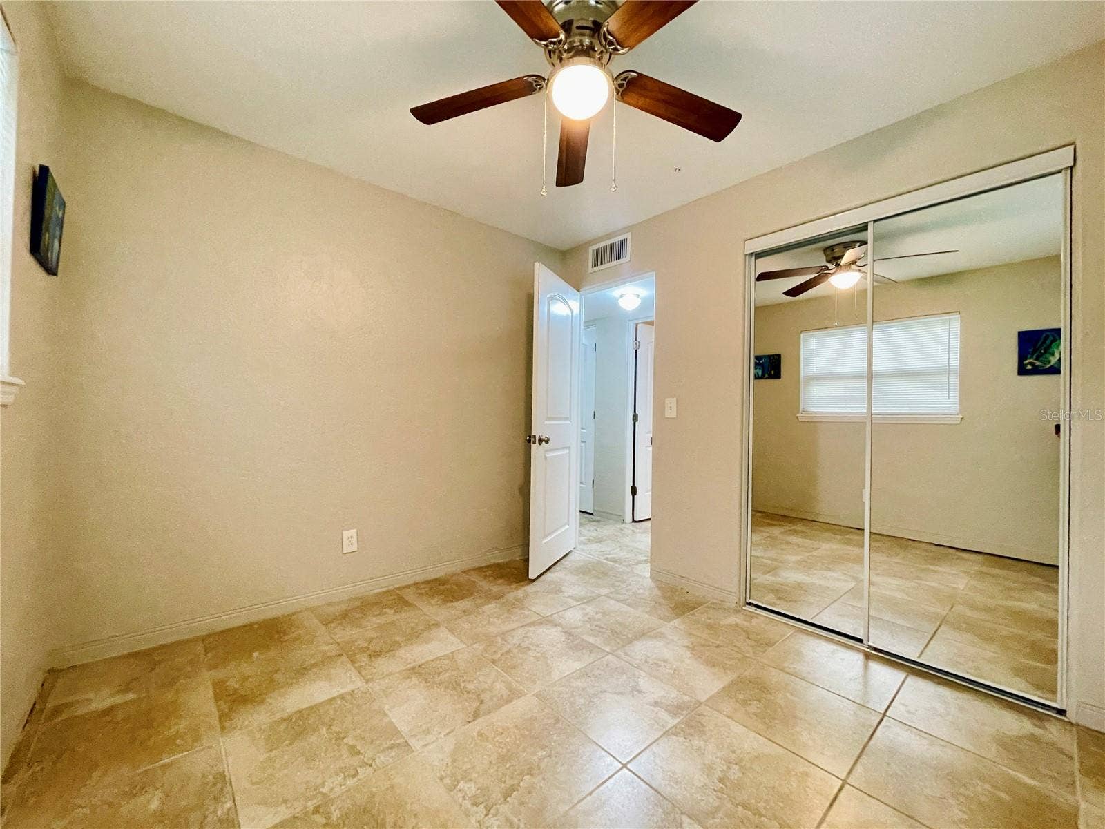 A second view of the guest bedroom highlights the mirrored closet doors, providing convenient storage while reflecting light throughout the room.