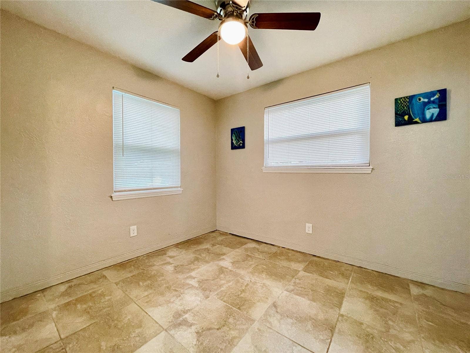 Natural light from two windows brightens this versatile guest bedroom, complemented by a ceiling fan for added comfort.