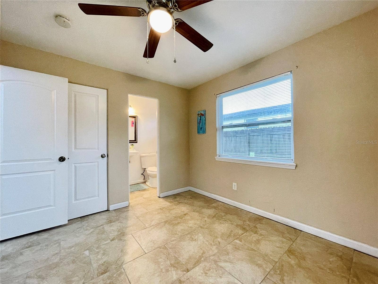 Another view of the bright bedroom with neutral colors and ceiling fan.