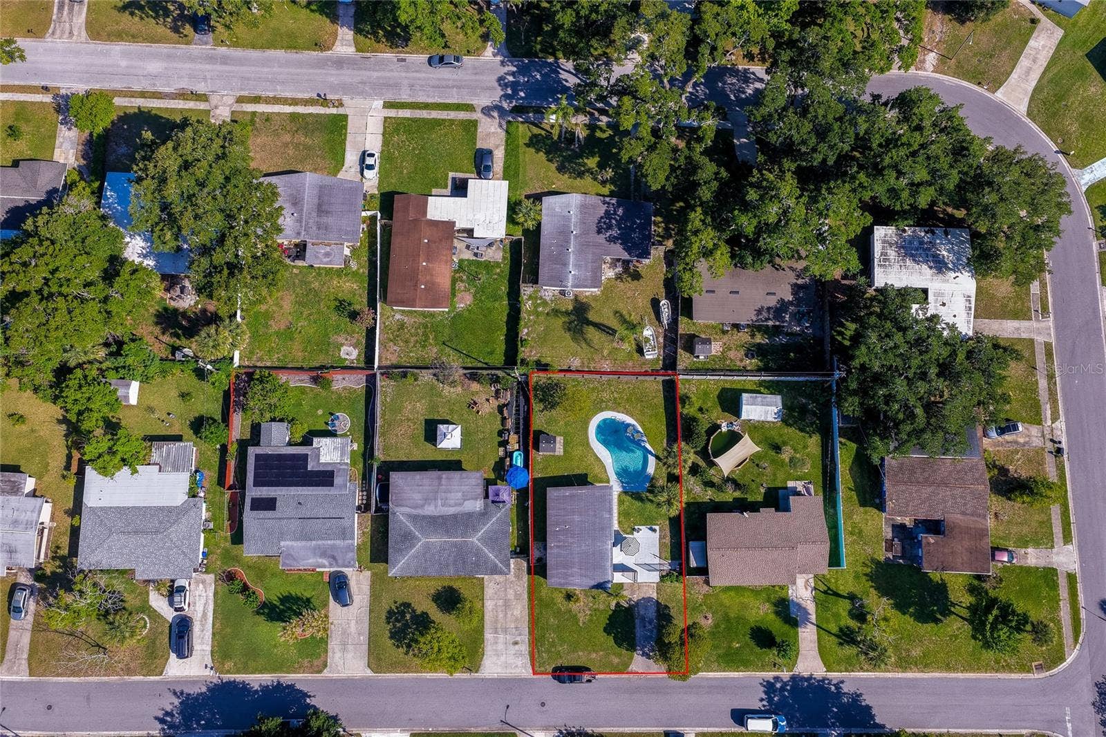 Top-down lot aerial outlined in red, clearly defining the property boundaries, spacious yard layout, and pool placement relative to surrounding neighbors.