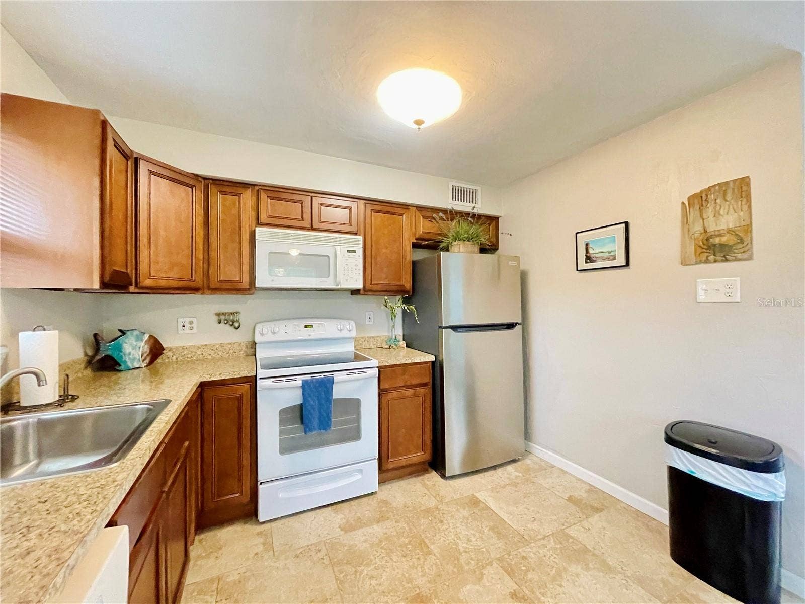 A closer view highlights the abundant cabinetry and counter space, stainless steel refrigerator, electric range, built-in microwave, and convenient workspace.