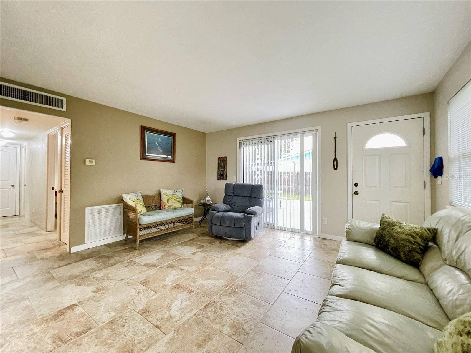 Sunlit living space highlighting a sliding glass door that leads to the backyard.