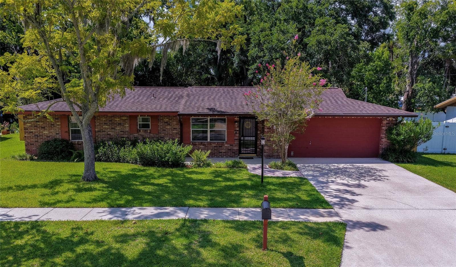 789 BENNETT ROAD, South Daytona, FL 32119 Charming ranch-style home featuring a spacious front yard, mature trees, and a wide concrete driveway leading to a two-car garage.