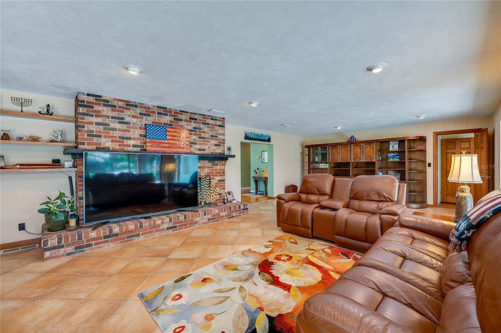 697 JOHN ANDERSON DRIVE, Ormond Beach, FL 32176 Family room with TV covering part of double-sided fireplace