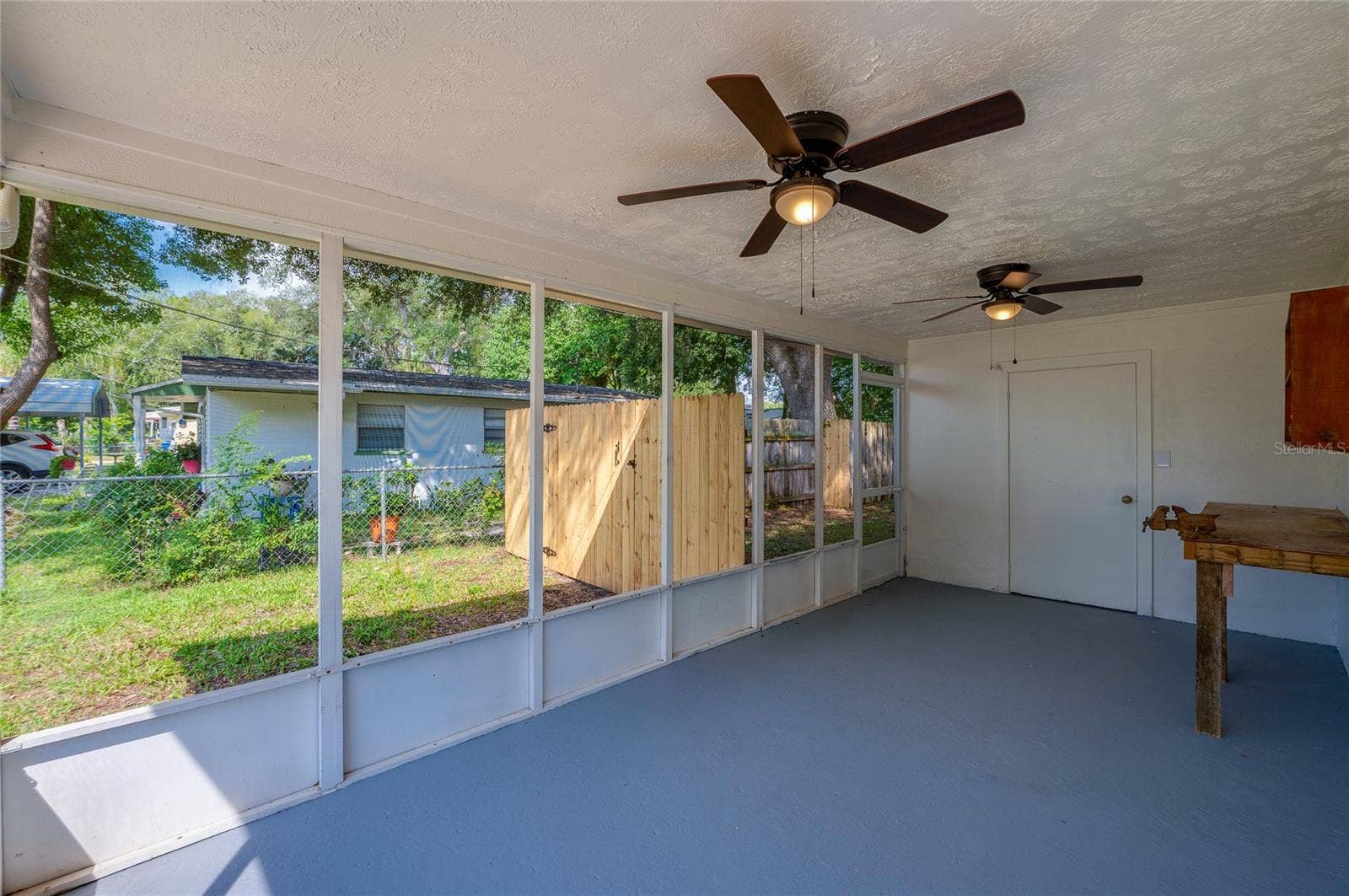 1220 LEON LANE, Daytona Beach, FL 32117 Spacious screened porch provides a comfortable outdoor living area with ceiling fans, perfect for relaxing or entertaining year-round.