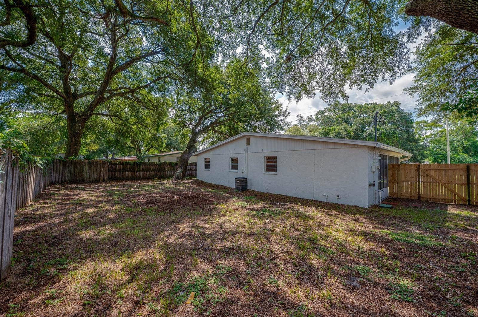 1220 LEON LANE, Daytona Beach, FL 32117 Generous backyard with privacy fencing and established trees creating a peaceful outdoor setting.